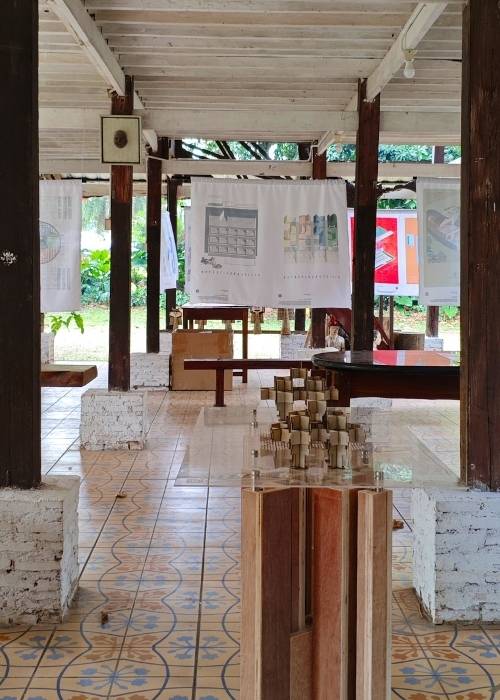 Maket interaktif dan poster program Kampung Gotong Royong Menteng Tenggulun kolaborasi IAI Jakarta x KemenPKP oleh YPA Architecture Studio di Bintaro Design District BDD 2026 Tanah Tinggal, menampilkan desain teknis Rumah Bapak Muslim oleh Ar. Yudha Prasetyo dan Rumah Ibu Mutiah oleh Ar. Titik Efianti & Ricky Geri Ariestivo.