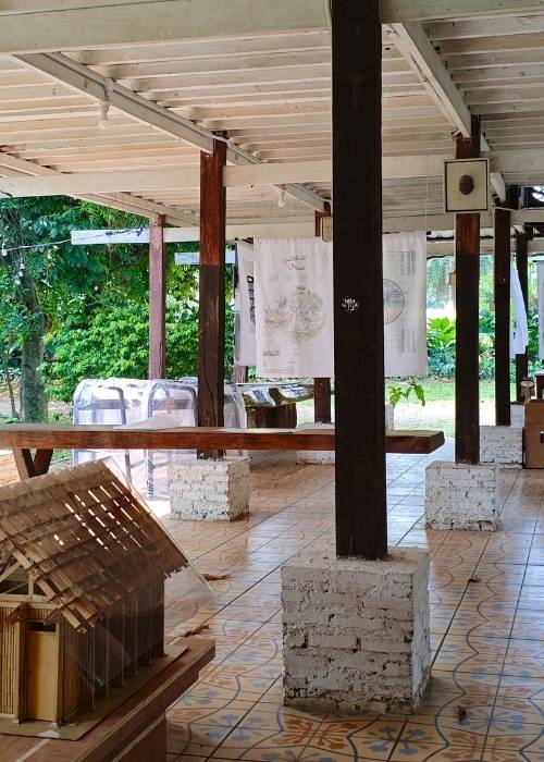 Maket interaktif dan poster program Kampung Gotong Royong Menteng Tenggulun kolaborasi IAI Jakarta x KemenPKP oleh YPA Architecture Studio di Bintaro Design District BDD 2026 Tanah Tinggal, menampilkan desain teknis Rumah Bapak Muslim oleh Ar. Yudha Prasetyo dan Rumah Ibu Mutiah oleh Ar. Titik Efianti & Ricky Geri Ariestivo.