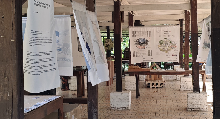 Maket interaktif dan poster program Kampung Gotong Royong Menteng Tenggulun kolaborasi IAI Jakarta x KemenPKP oleh YPA Architecture Studio di Bintaro Design District BDD 2026 Tanah Tinggal, menampilkan desain teknis Rumah Bapak Muslim oleh Ar. Yudha Prasetyo dan Rumah Ibu Mutiah oleh Ar. Titik Efianti & Ricky Geri Ariestivo.