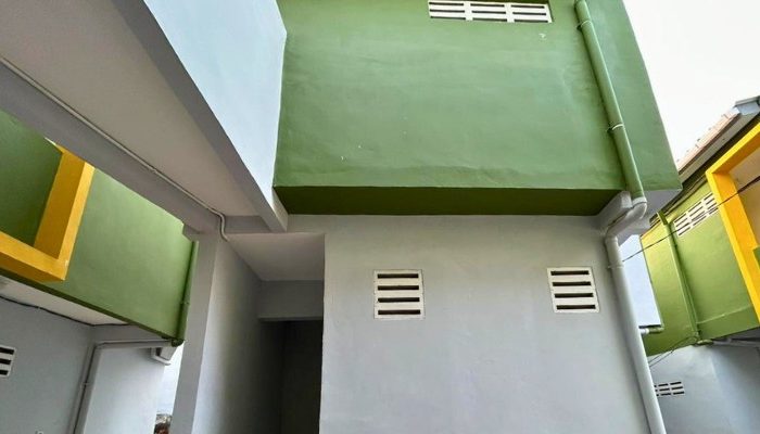 A sustainable urban housing project featuring compact modern residences, a pedestrian-friendly environment, and a landscaped public space with a pond and greenery. The area integrates eco-friendly elements such as green facades, vertical gardens, and natural ventilation.