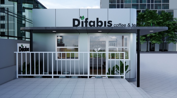 The interior of Cafe Difabis features a modern and inclusive design, incorporating wood elements and warm lighting. The ergonomic barista area is designed for accessibility, showcasing a professional coffee machine, open storage shelves, and a well-organized food display.