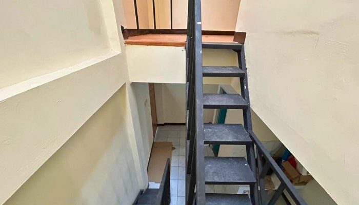 A sustainable urban housing project featuring compact modern residences, a pedestrian-friendly environment, and a landscaped public space with a pond and greenery. The area integrates eco-friendly elements such as green facades, vertical gardens, and natural ventilation.