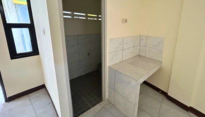 A sustainable urban housing project featuring compact modern residences, a pedestrian-friendly environment, and a landscaped public space with a pond and greenery. The area integrates eco-friendly elements such as green facades, vertical gardens, and natural ventilation.