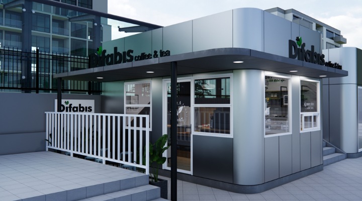 The interior of Cafe Difabis features a modern and inclusive design, incorporating wood elements and warm lighting. The ergonomic barista area is designed for accessibility, showcasing a professional coffee machine, open storage shelves, and a well-organized food display.