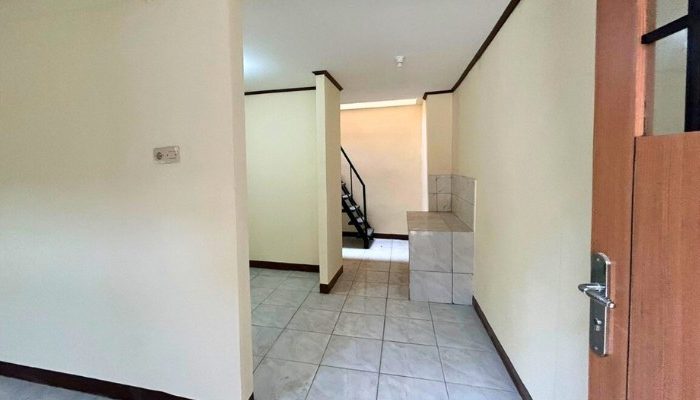 A sustainable urban housing project featuring compact modern residences, a pedestrian-friendly environment, and a landscaped public space with a pond and greenery. The area integrates eco-friendly elements such as green facades, vertical gardens, and natural ventilation.