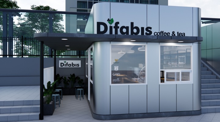 The interior of Cafe Difabis features a modern and inclusive design, incorporating wood elements and warm lighting. The ergonomic barista area is designed for accessibility, showcasing a professional coffee machine, open storage shelves, and a well-organized food display.