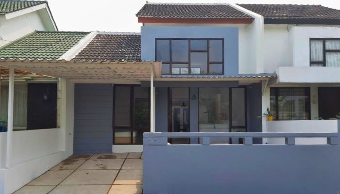 Front view of a modern two-story tropical house in Bintaro with large windows, a soft blue façade, and a functional carport integrated into the minimalist design.