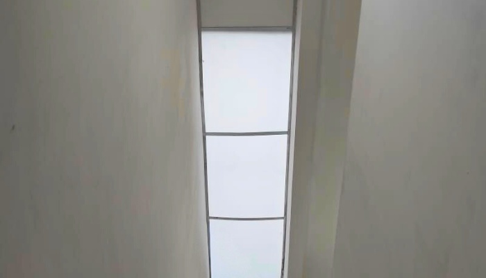 The main façade and interior of WU House in North Jakarta, featuring a tropical modern design with exposed concrete materials, natural wood, and large glass openings that optimize natural lighting and air circulation.