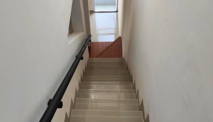 The main façade and interior of WU House in North Jakarta, featuring a tropical modern design with exposed concrete materials, natural wood, and large glass openings that optimize natural lighting and air circulation.