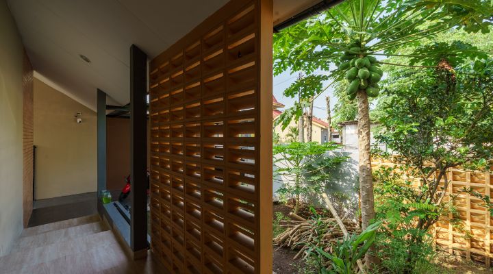 A modern tropical house with lattice walls, a green garden, and natural lighting in Purbalingga, designed by YPA Architecture Studio in 2024.