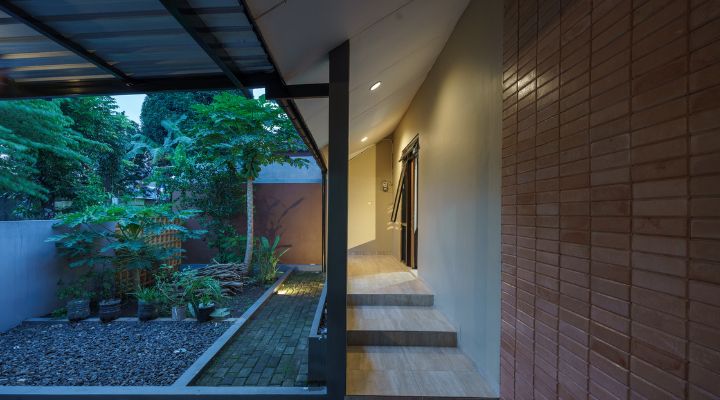 A modern tropical house with lattice walls, a green garden, and natural lighting in Purbalingga, designed by YPA Architecture Studio in 2024.