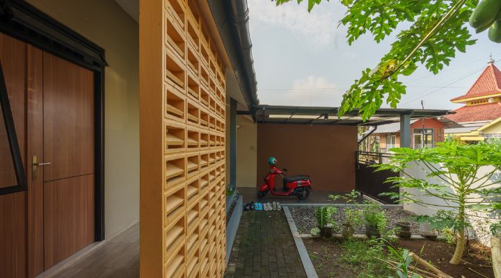 A modern tropical house with lattice walls, a green garden, and natural lighting in Purbalingga, designed by YPA Architecture Studio in 2024.