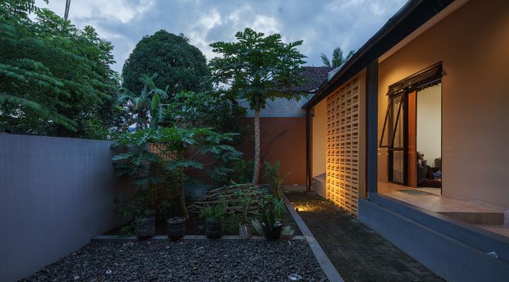 A modern tropical house with lattice walls, a green garden, and natural lighting in Purbalingga, designed by YPA Architecture Studio in 2024.