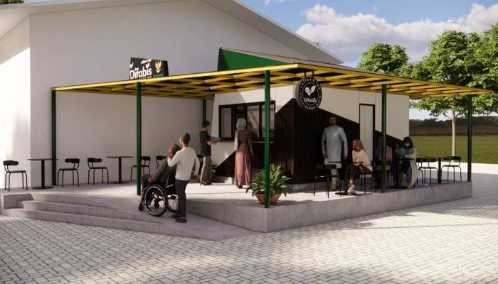 The exterior and interior design of Cafe Difabis RSUD Kebayoran Lama by YPA Architecture Studio features a small building with a transparent canopy, open seating area, and inclusive layout that is disability friendly.