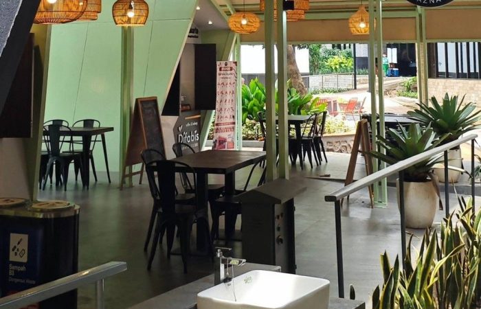 Tampak bangunan Café Difabis Coffee & Bakery karya YPA Architecture Studio di kawasan Kantor Walikota Jakarta Timur dengan atap pelana asimetris, façade hijau pastel, dan area terbuka yang ramah bagi semua pengguna.