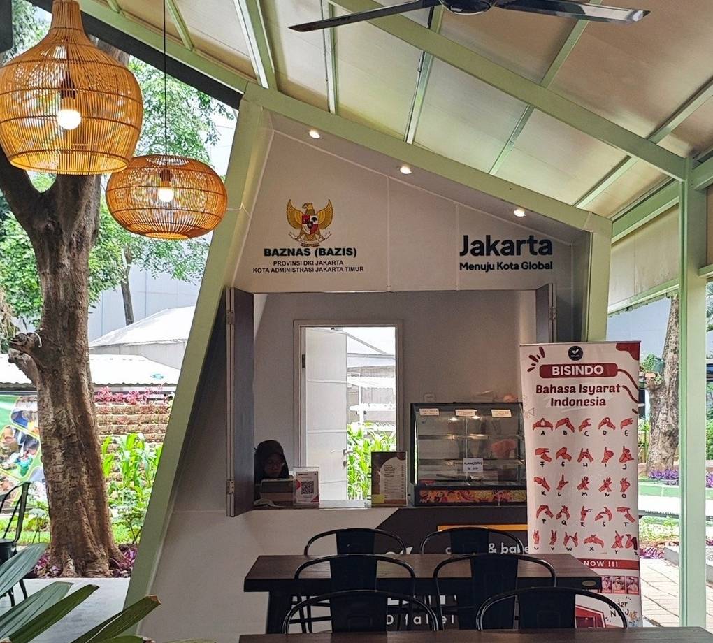 Tampak bangunan Café Difabis Coffee & Bakery karya YPA Architecture Studio di kawasan Kantor Walikota Jakarta Timur dengan atap pelana asimetris, façade hijau pastel, dan area terbuka yang ramah bagi semua pengguna.