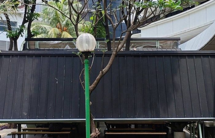 Tampak bangunan Café Difabis Coffee & Bakery karya YPA Architecture Studio di kawasan Kantor Walikota Jakarta Timur dengan atap pelana asimetris, façade hijau pastel, dan area terbuka yang ramah bagi semua pengguna.