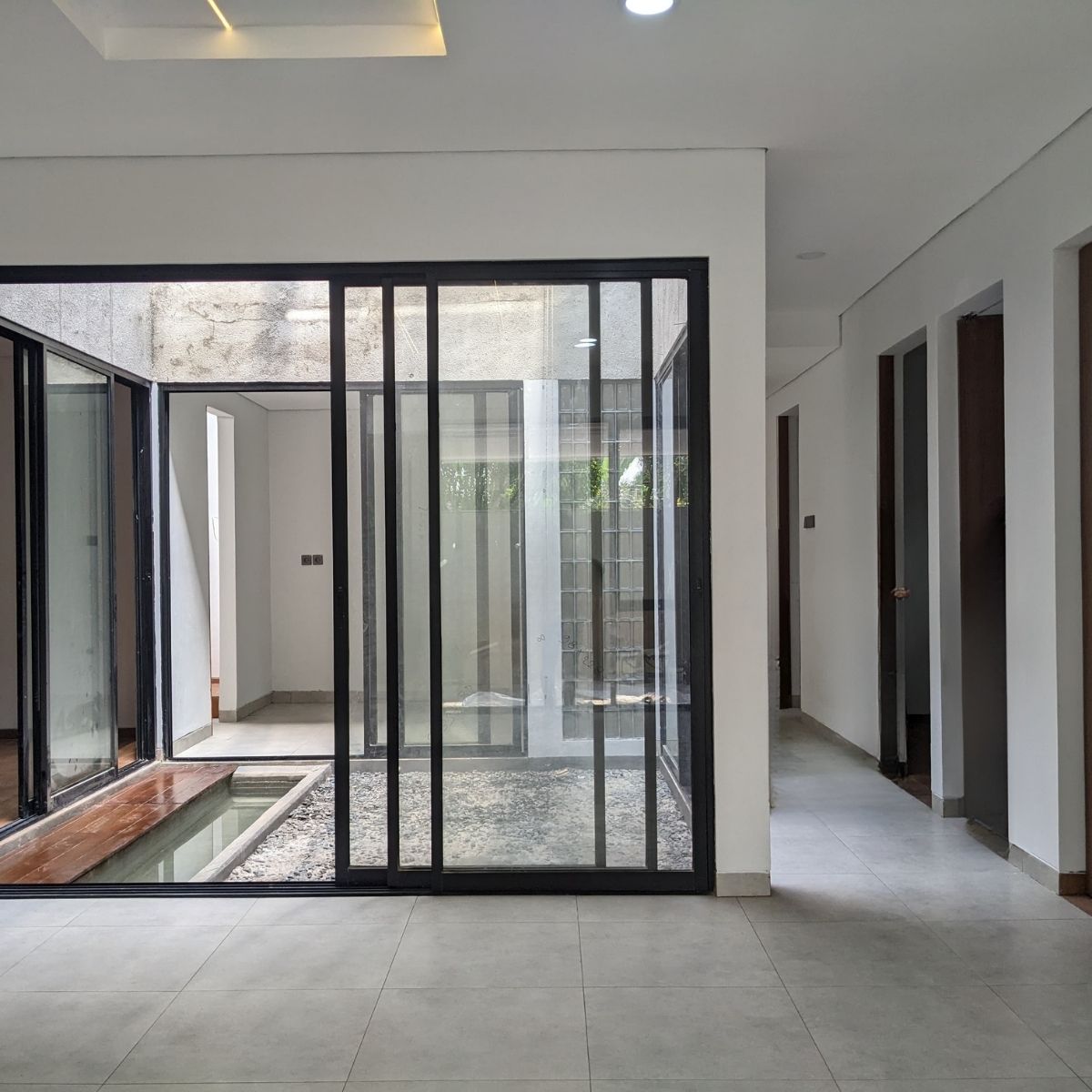 Proyek Adhara House di Tangerang Selatan karya YPA Architecture Studio dan Barakaja Construction menampilkan fasad modern dengan aksen merah, dinding roster beton, dan inner courtyard minimalis dengan kolam air yang terintegrasi dengan interior rumah yang luas.